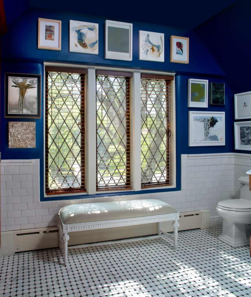 Mans bathroom with blue paint and white tile and gallery wall