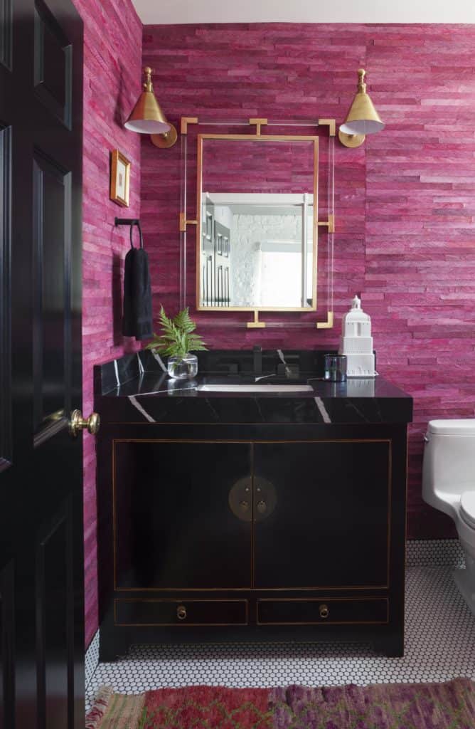 Designer powder room with pink wood wallcovering, brass sconces and beautiful black vanity in ASI Denver Showroom