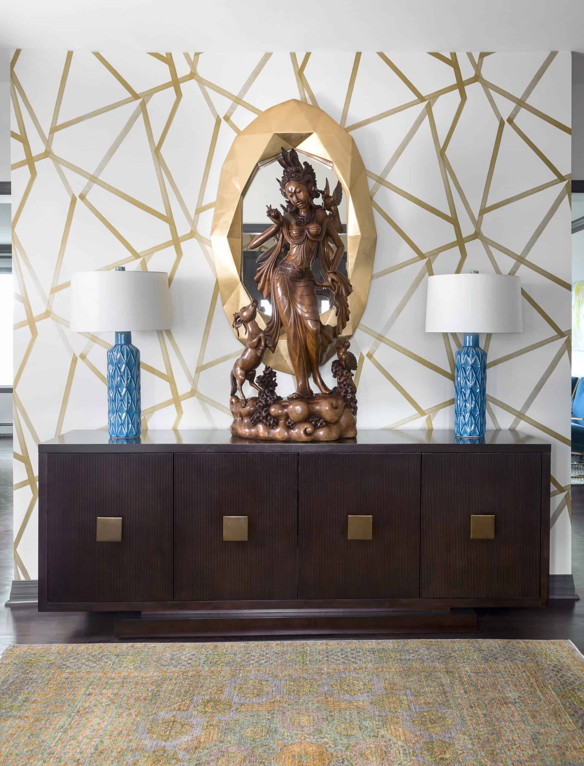 Simple, stunning entry with geometric gold wallpaper, chunky mirror and ebonized finish buffet
