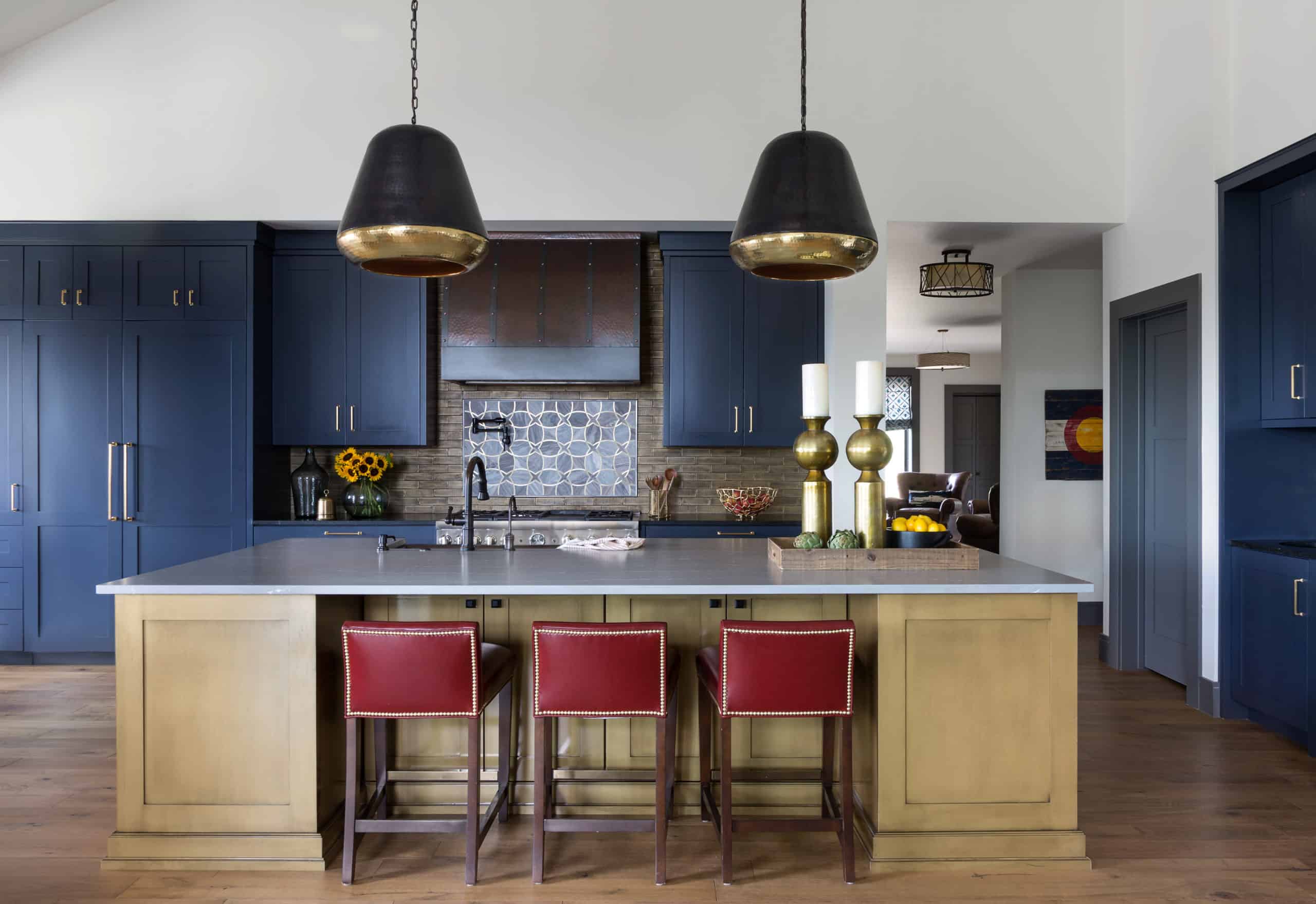 Navy cabinets and red leather stools with huge kitchen pendants