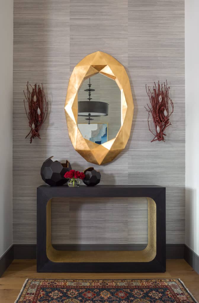 Entry with grasscloth wallpaper, black console and gold leaf geometric mirror