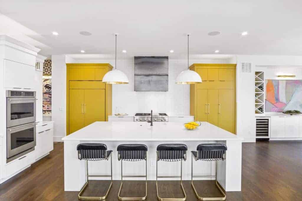 Sleek kitchen with bright yellow cabinets and industrial kitchen hood
