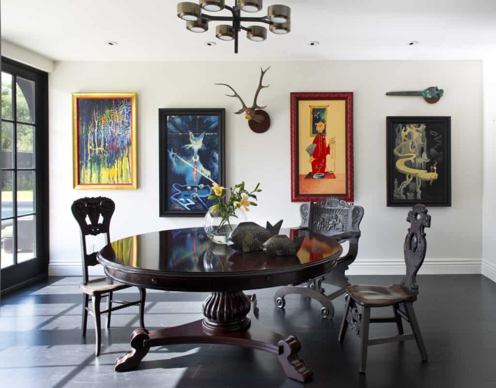 Curated dining area with mixed antique table and chairs and cheerful art