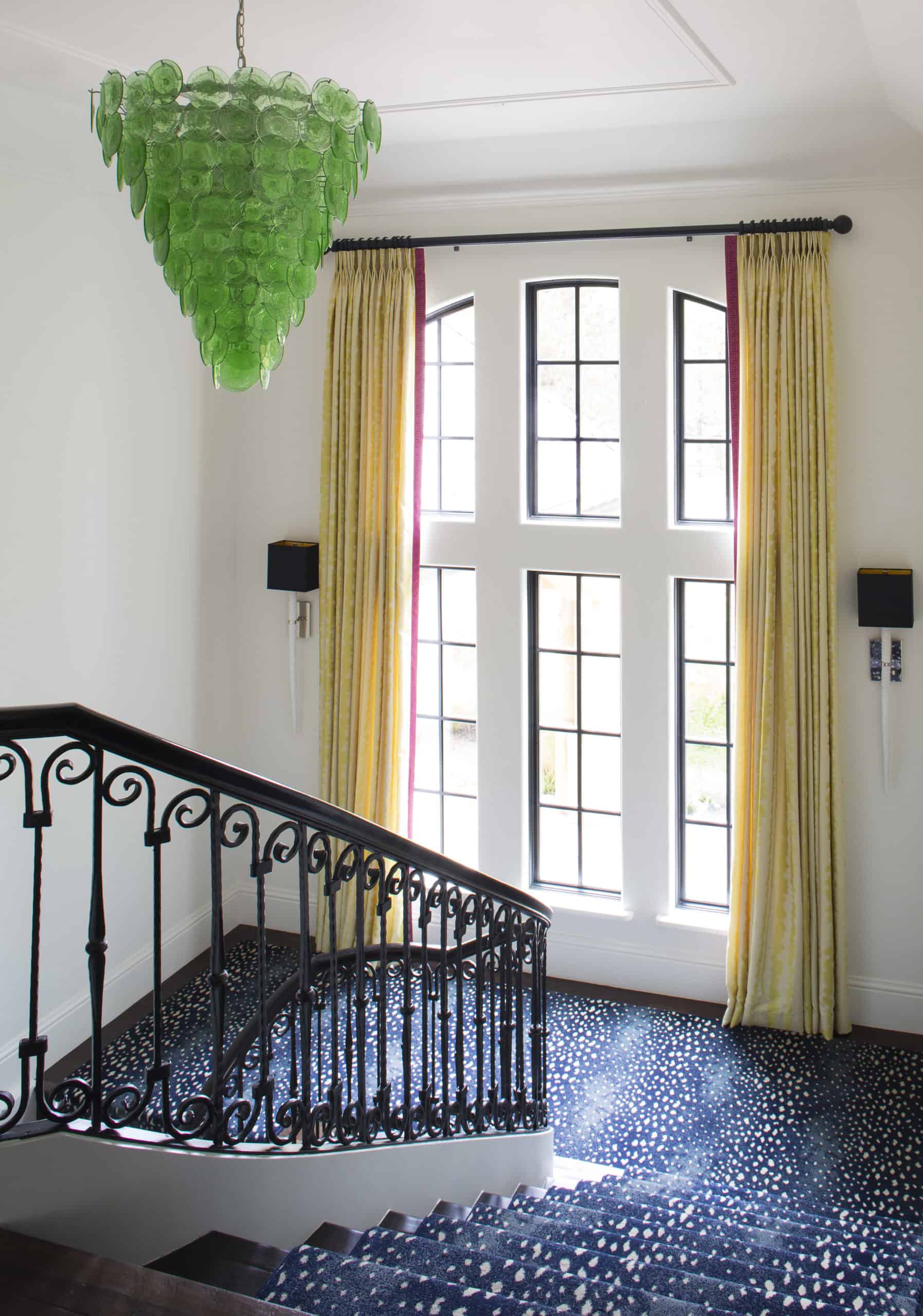 Staircase with green murano glass chandelier, 9 foot draperies, plush stair runner and rounded wood banister