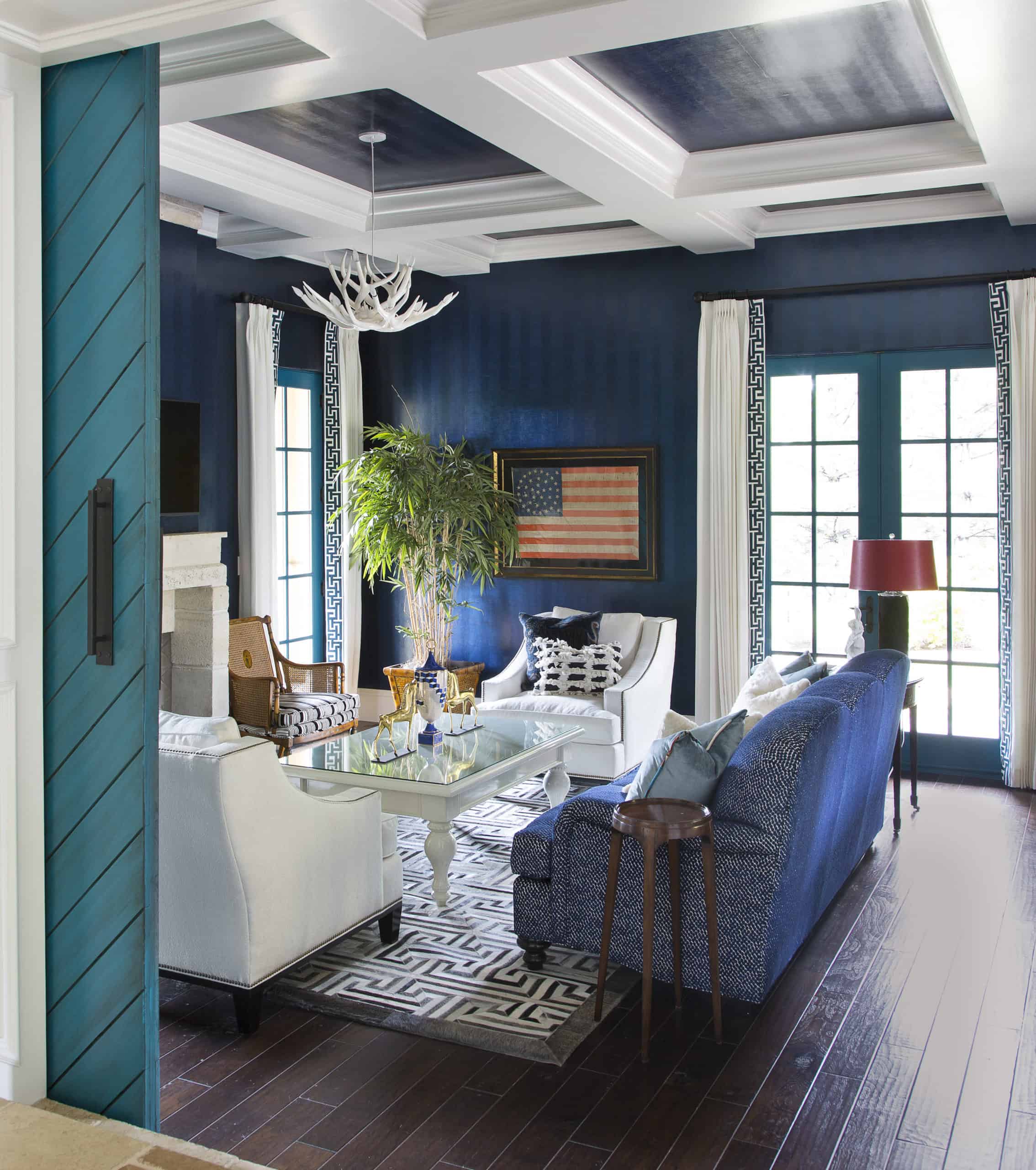 Masculine study with fireplace, turquoise barn door, blue wallpapered ceiling and antler chandelier