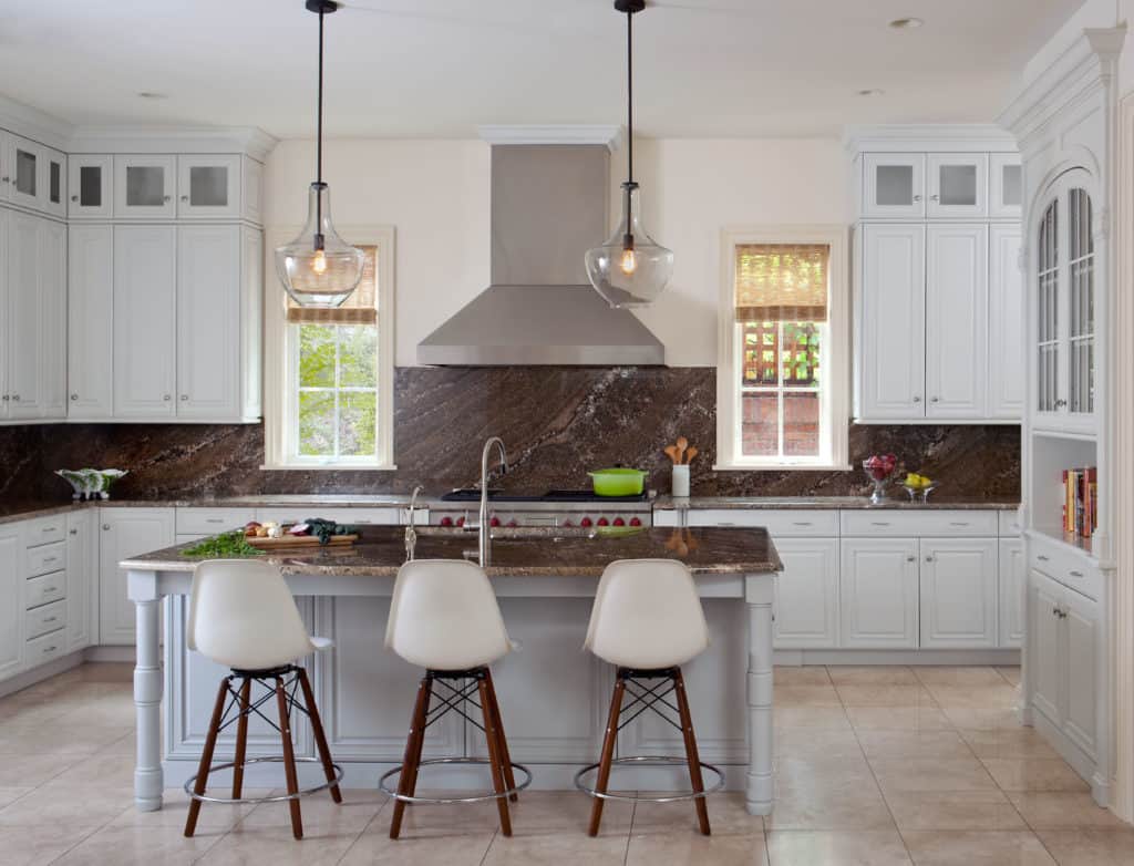 Neutral kitchen with modern counter stools, glass pendants and marble slab backsplash