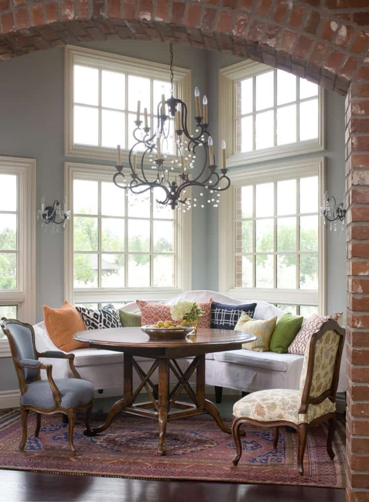 Gorgeous breakfast room with large windows, bench seating, chandelier and brick entry