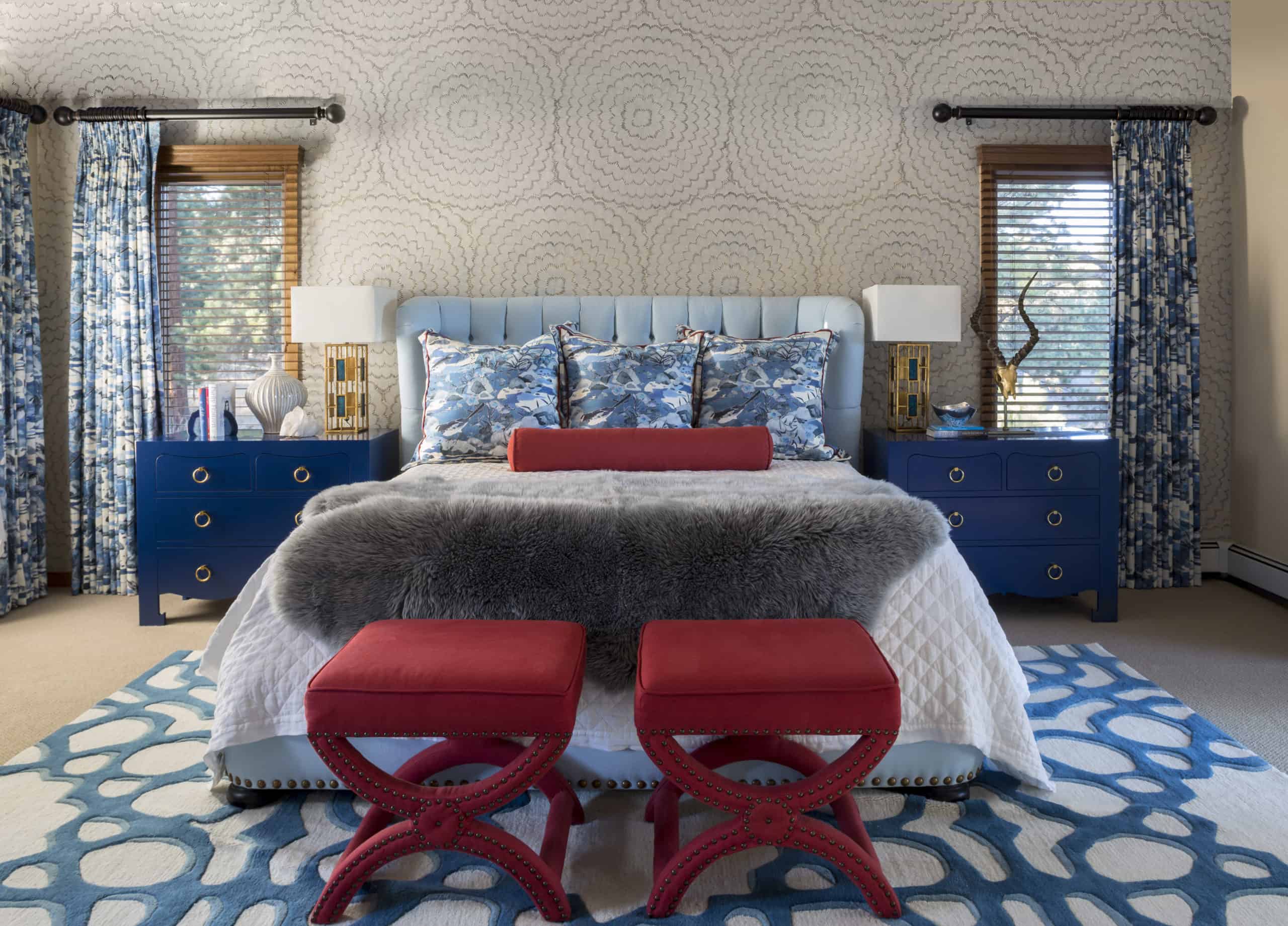 Creamy textured bedroom wallcovering, custom bedframe and red upholstered stools