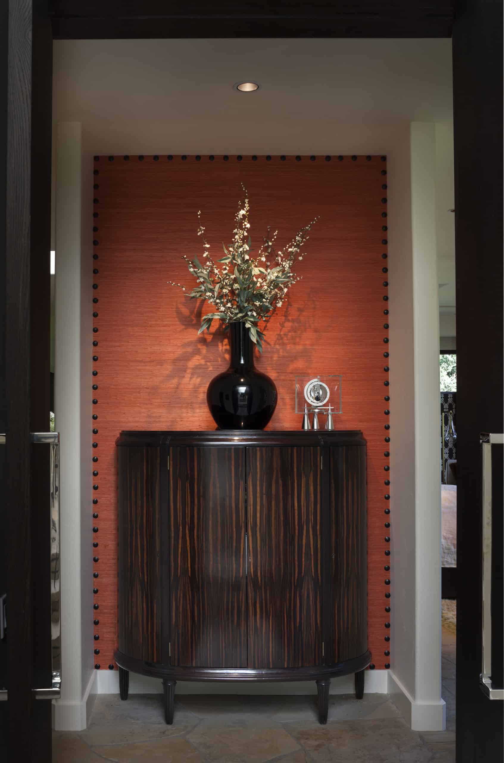Grasscloth on accent wall in hallway with gorgeous cabinet
