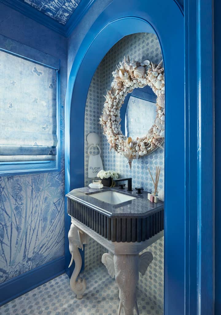 Blue powder room with elephant vanity and shell mirror