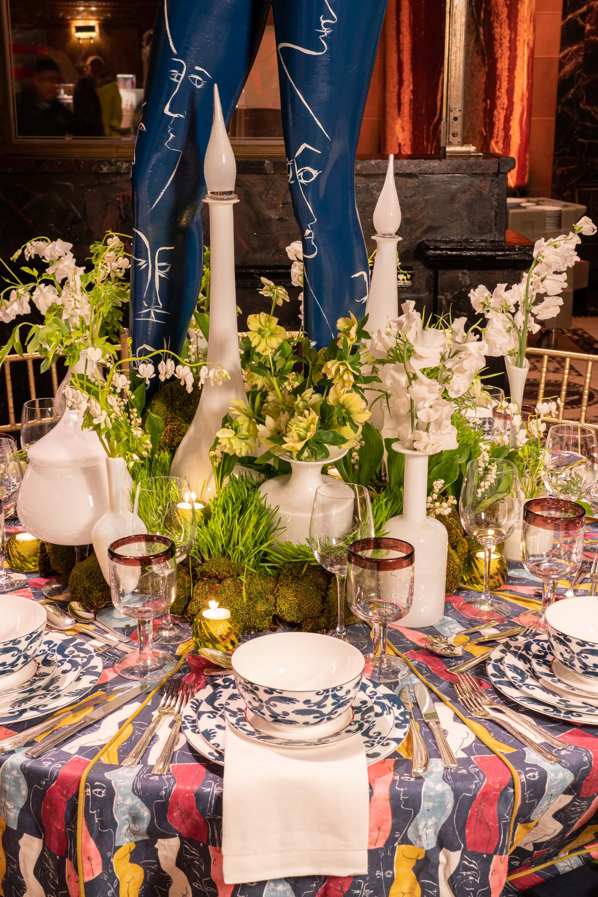 tablescape with a white glass bottles among greenery as a centerpiece