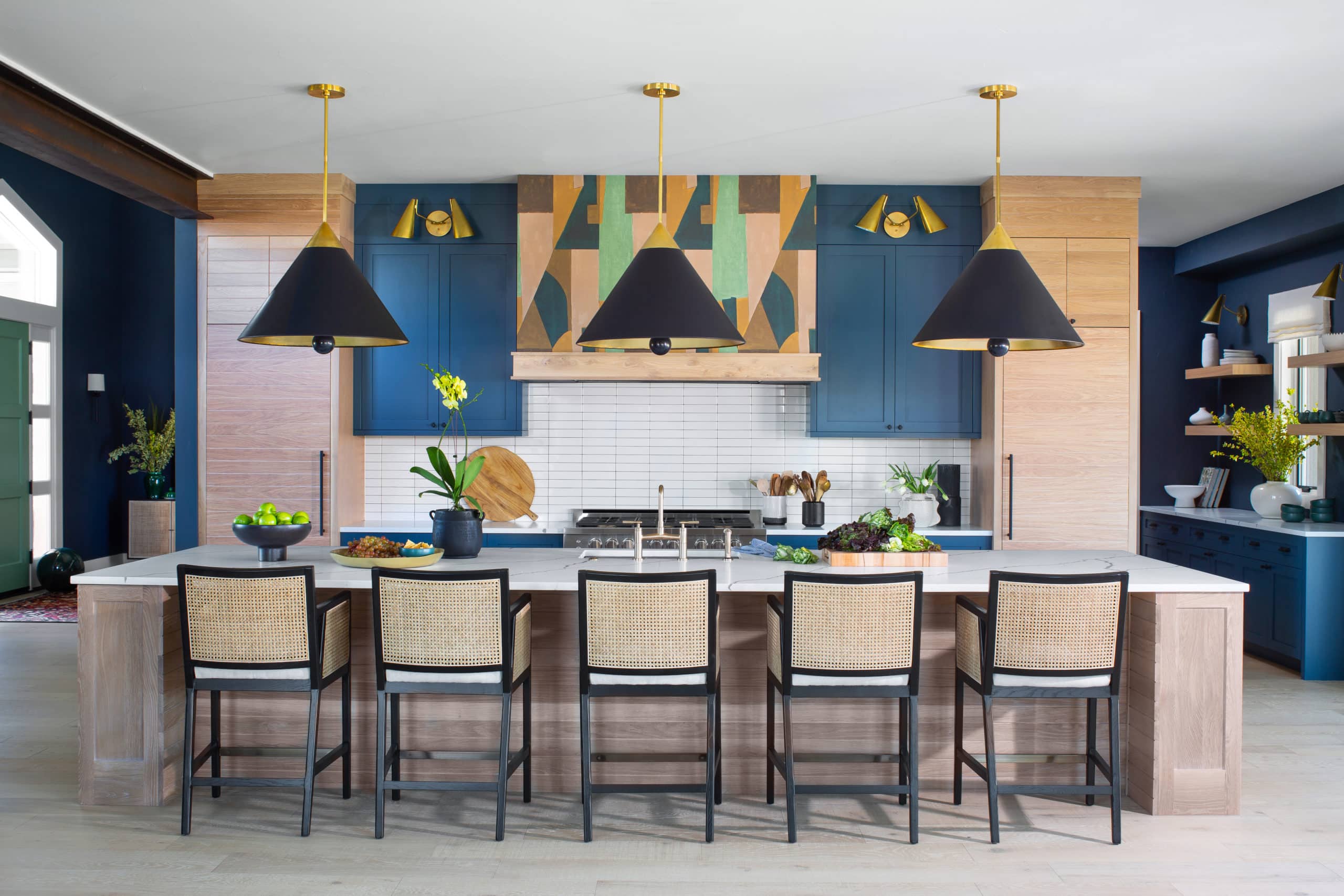 Kitchen in the Mighty Millions Show House 2021. Kelly Wearstler wallpaper on the range hood and cane backed counter chairs.