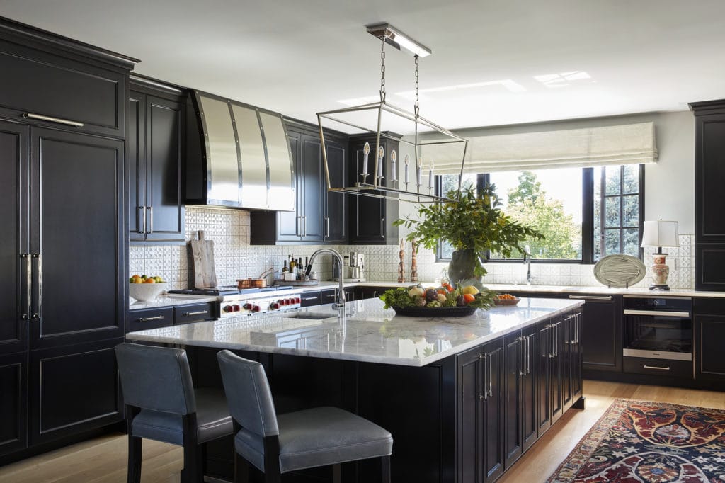 Bold black kitchen in Colorado with custom stainless steel range hood