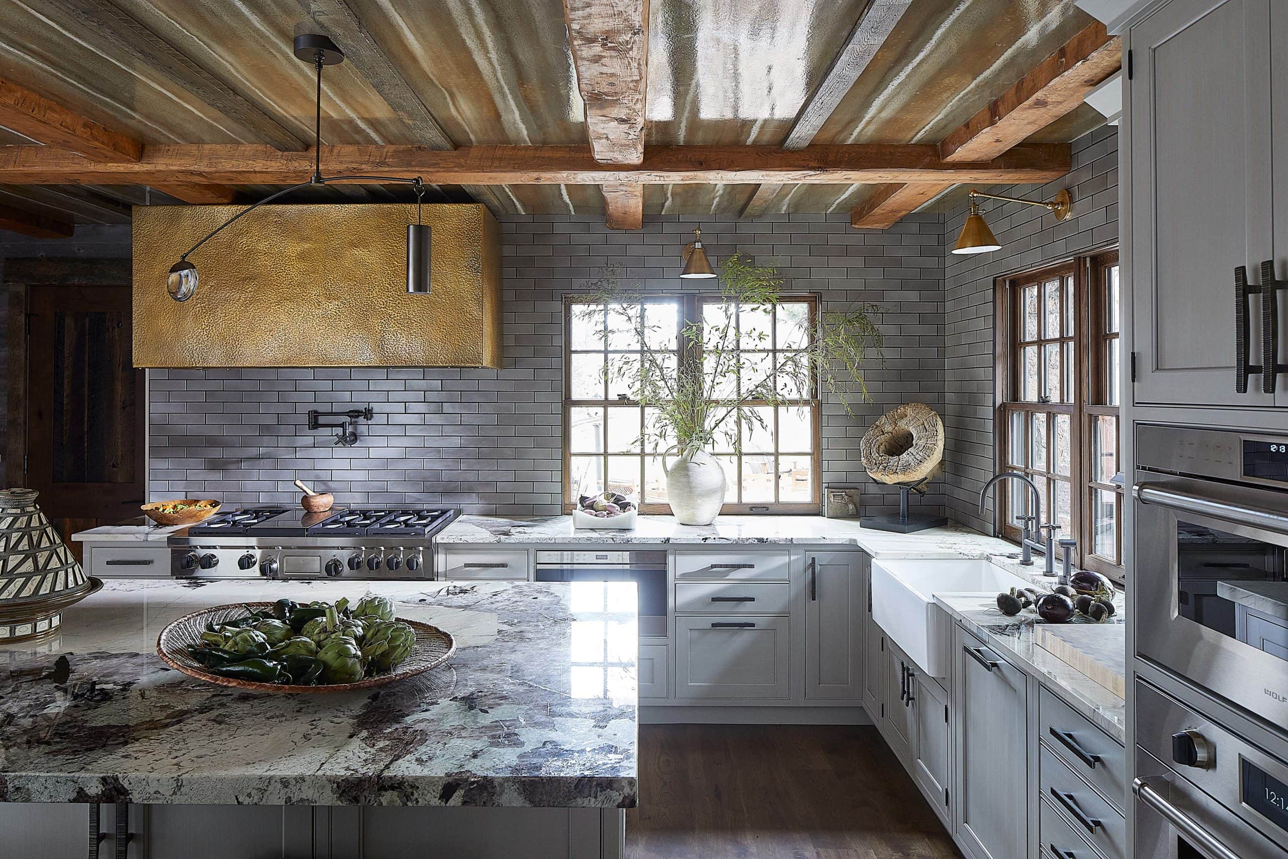 Modern ranch interior design kitchen with a custom hammered brass range hood. Farmhouse sink.