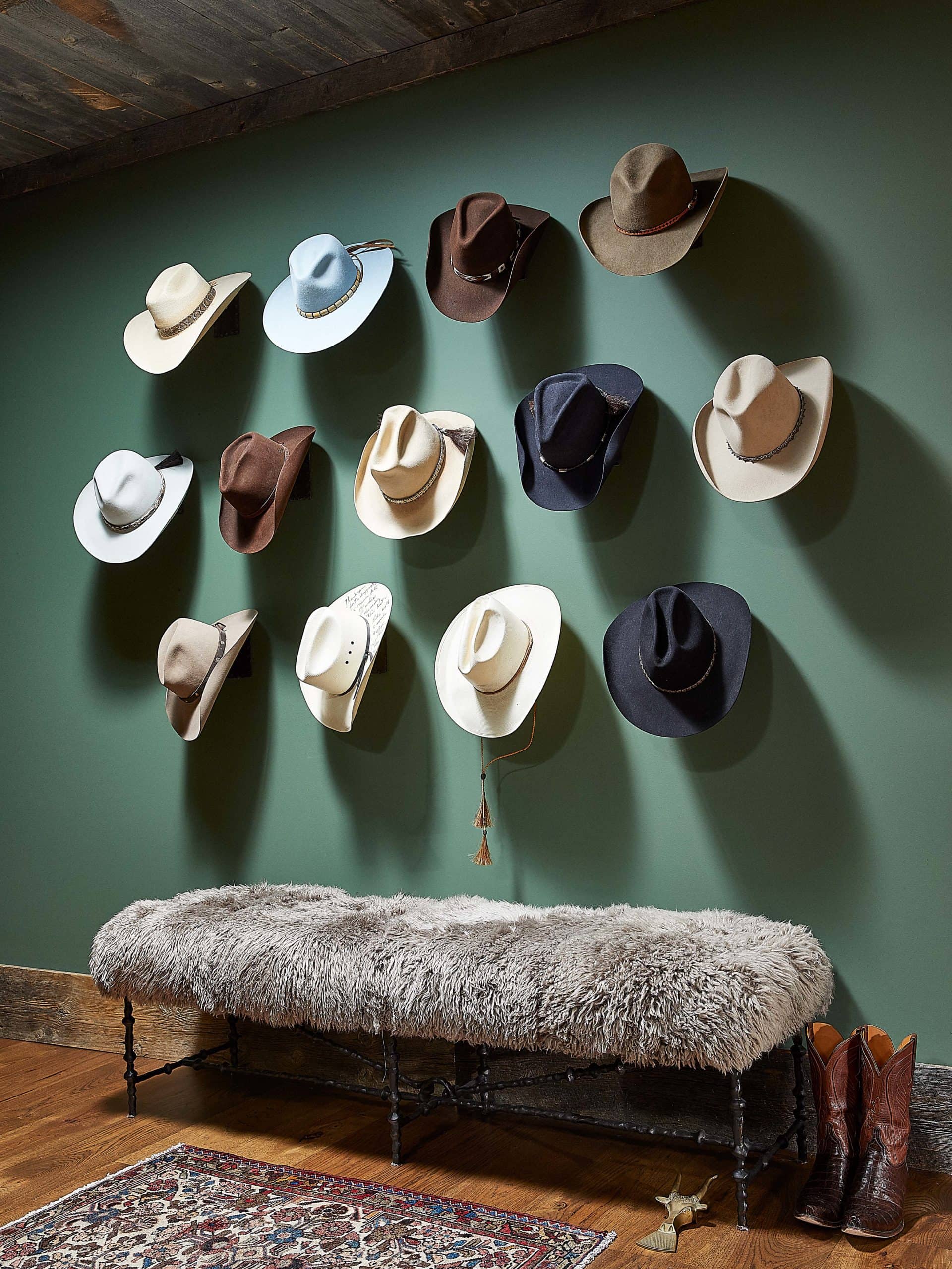 Decorative wall display collection of cowboy hats over a sheepskin covered bench.