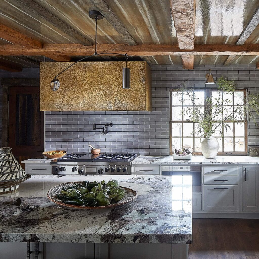 A white kitchen with a custom hammered brass range hood. Farmhouse sink.