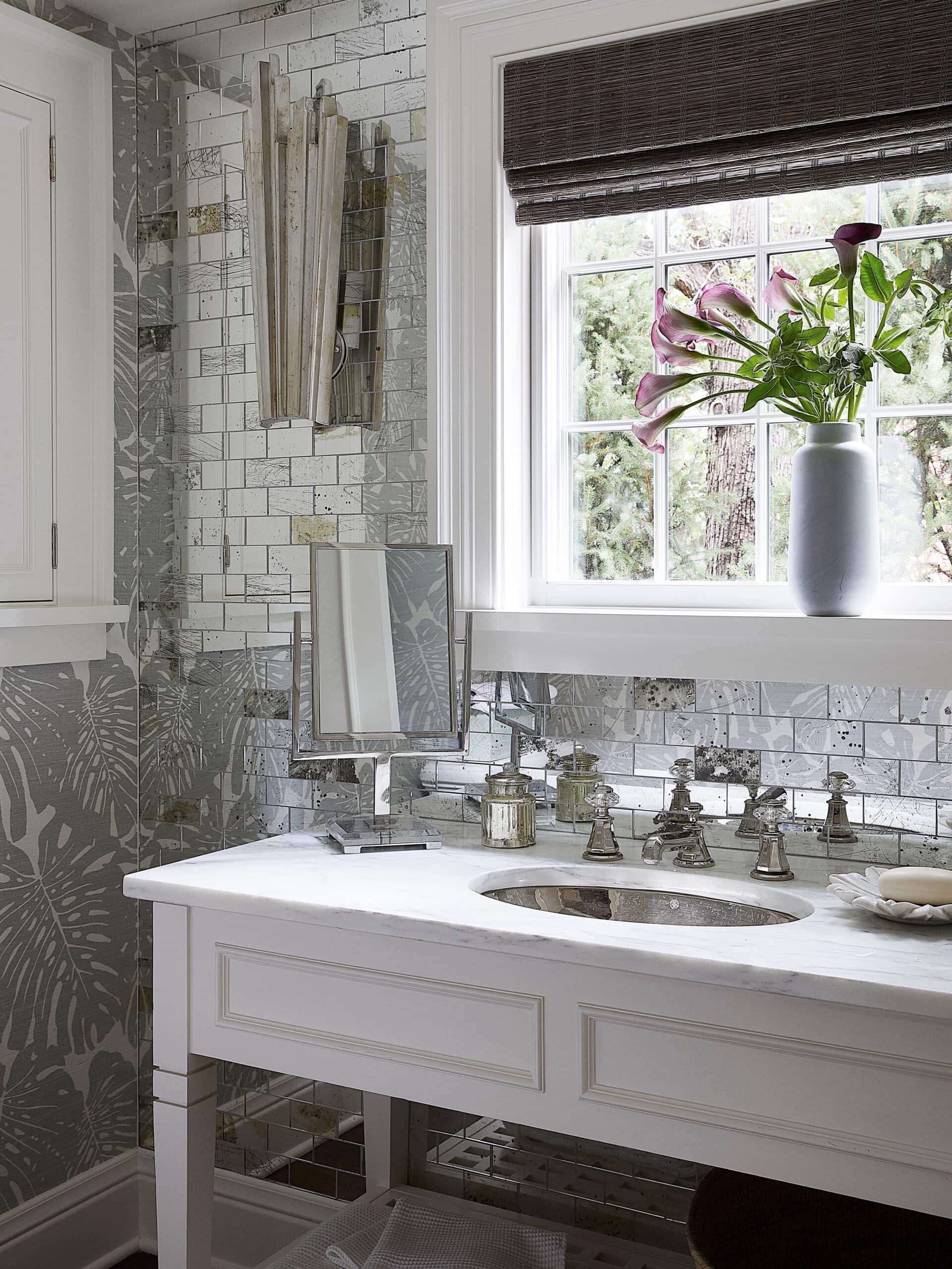 Powder room with antique mirrored subway tile and palm wallpaper