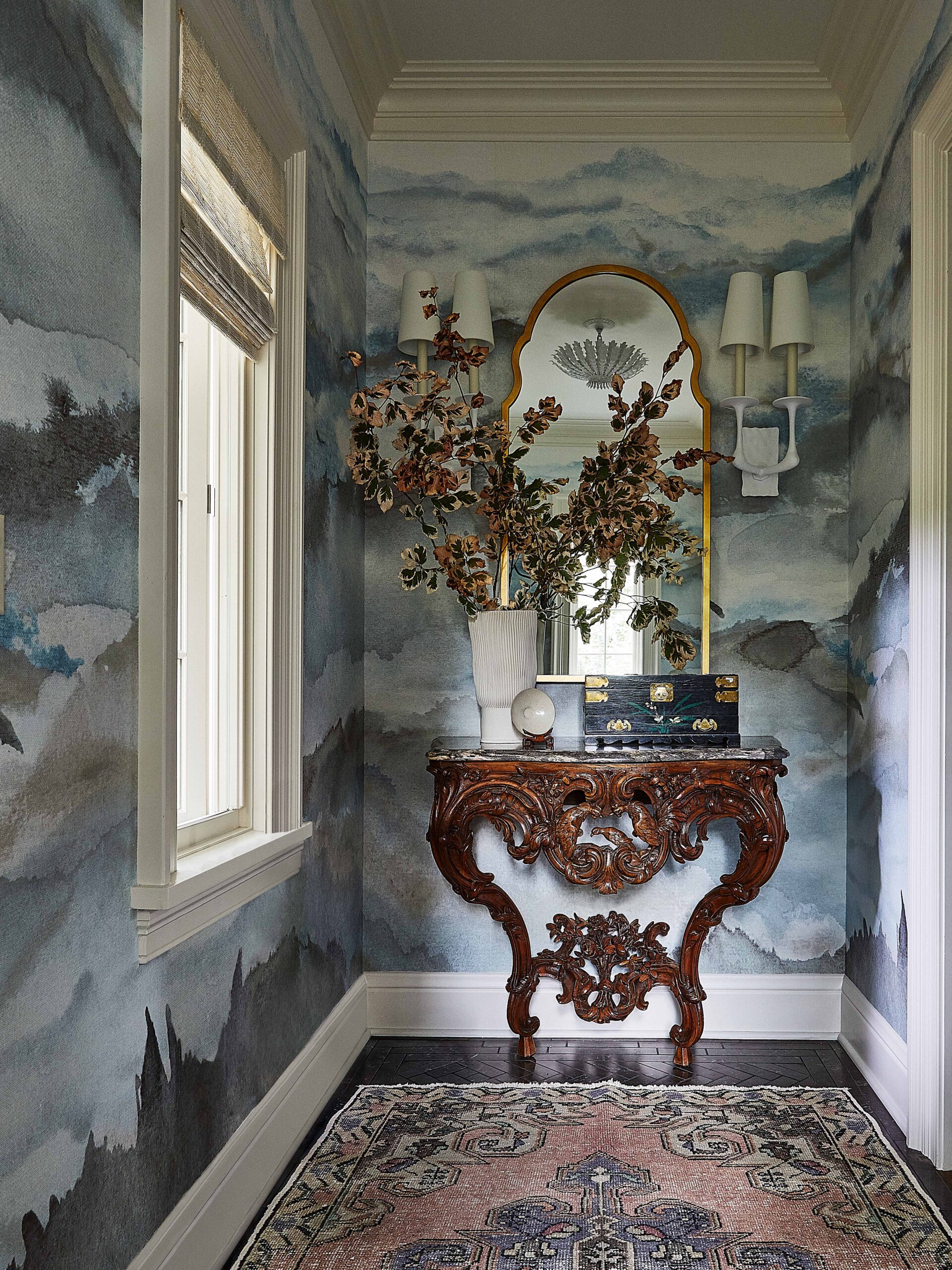 Home entry with blue scenic wallpaper and antique wood table and antique rug