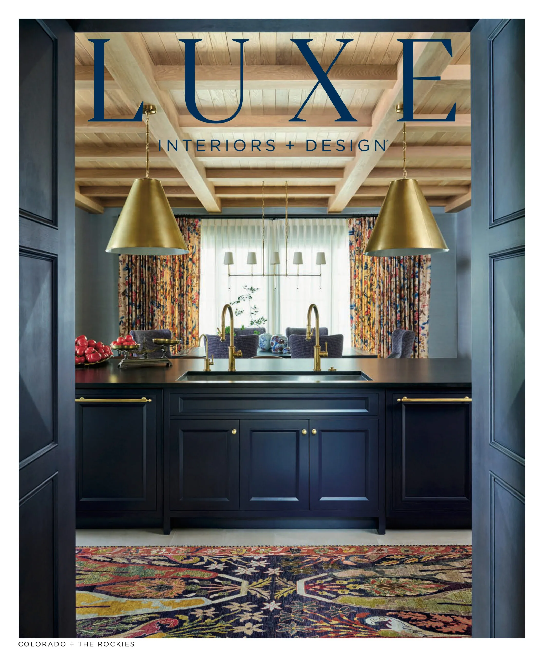 Luxury interior design Denver kitchen featured in LUXE Interiors + Design with custom navy cabinetry, brass lighting, and colorful textile accents in a Colorado home