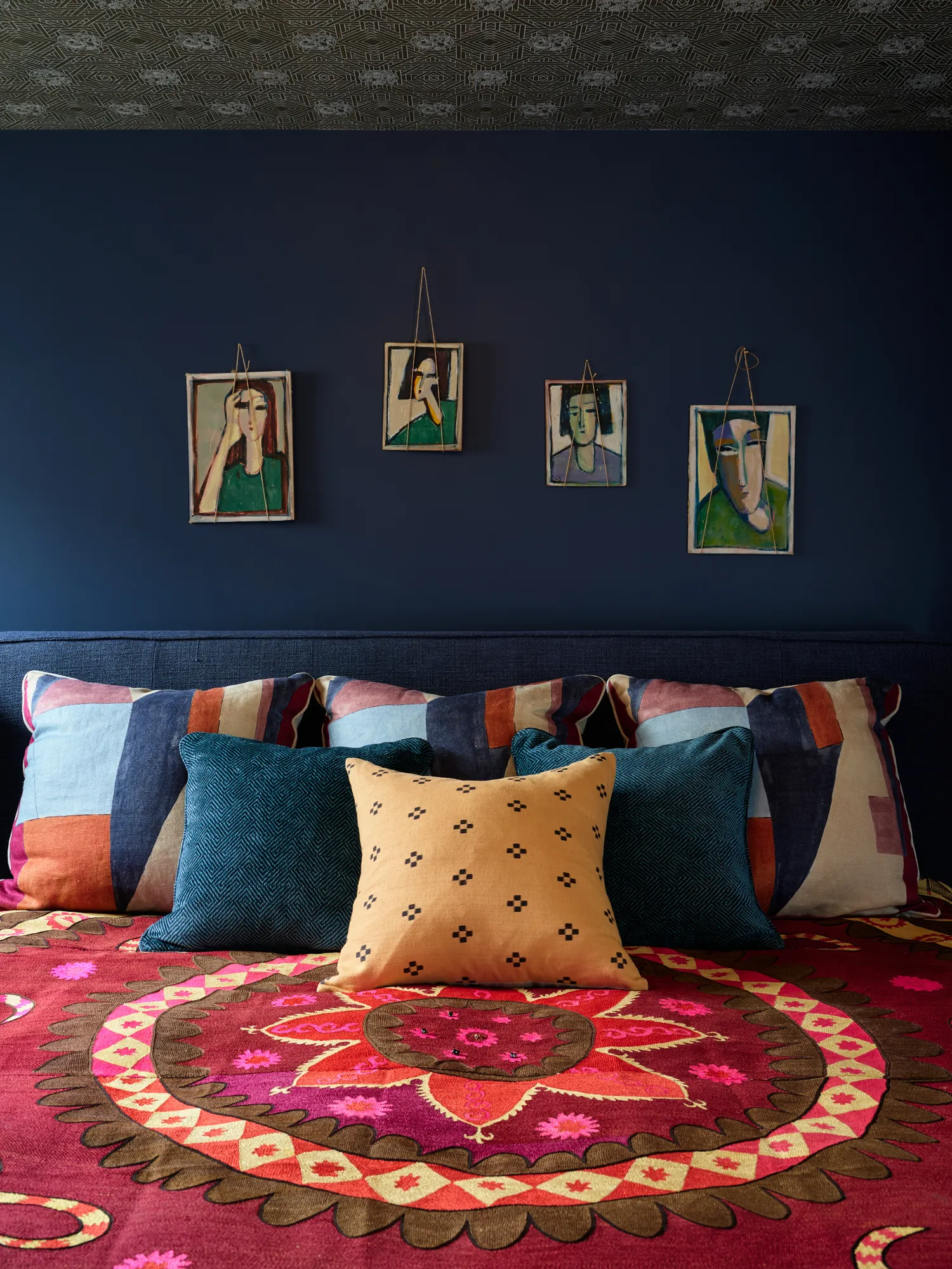 Bold bedroom with navy walls and colorful layered textiles in California home
