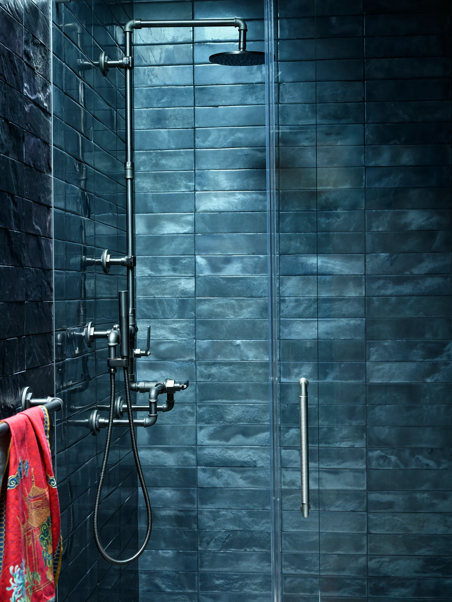 Dramatic blue tiled shower with brass fixtures in luxury coastal residence