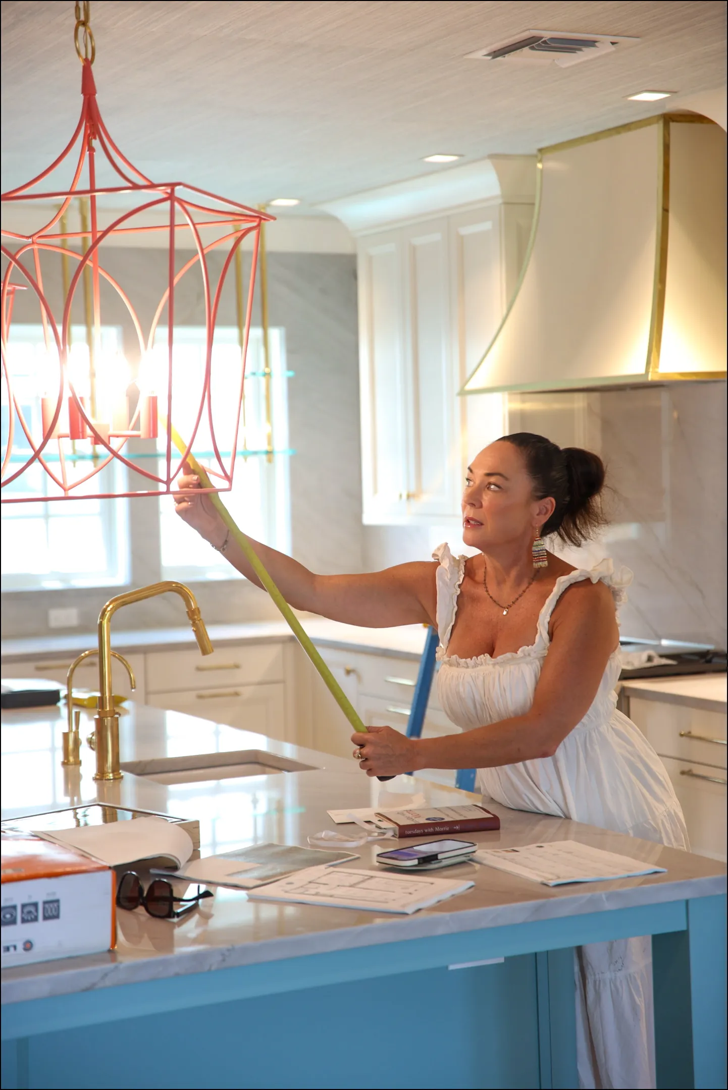 Andrea Schumacher measuring a pendant light during a Boca Grande, Florida vacation home installation